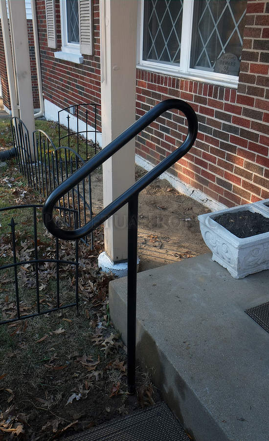 Tubular steel one post railing, capsule shaped, painted black for one step.